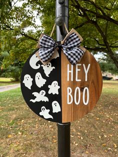 a wooden sign that says hey booo with ghost faces and black and white bows