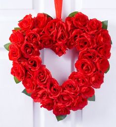 a heart shaped wreath with red roses hanging on a door