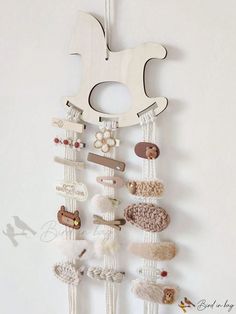 a white wall hanging with lots of different items on it's sides and a wooden hanger attached to the wall