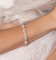 a bride's arm wearing a wedding dress and bracelet with three stones on it