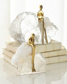 there is a gold statue sitting on top of some white books and holding a cane