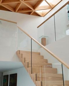 a stair case with glass railing and wooden handrail