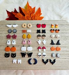 a wooden board topped with lots of different types of halloween decorations and pumpkins next to a maple leaf