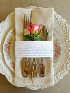 there is a place setting with silverware and flowers on the plate, along with a card