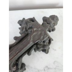 an ornate metal object on a white marble counter top with a wooden cross hanging from it's center