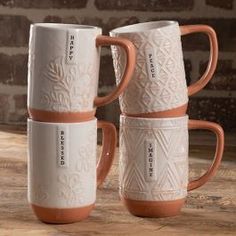 three coffee mugs sitting on top of a wooden table