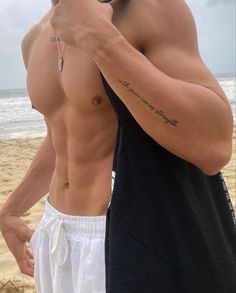 a shirtless man taking a selfie on the beach with his cell phone in his hand