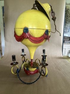 an old fashioned yellow machine with red and blue decorations on it's head, sitting on a table