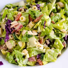 a salad with bacon, lettuce and other toppings in a white bowl