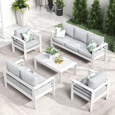 a group of white furniture sitting on top of a cement floor next to a green plant