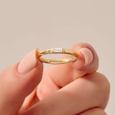 a woman's hand holding a yellow gold ring