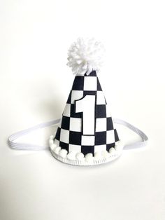 a black and white checkered party hat with pom - poms on it