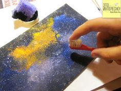 a person holding a toothbrush in front of a painting with yellow and blue colors