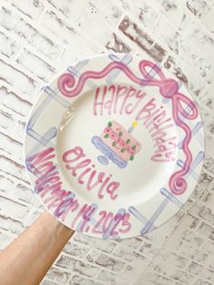 a hand holding a plate with a cake on it that says happy birthday annie may 2013