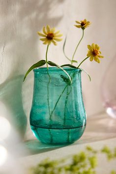 two yellow flowers in a blue vase on a table