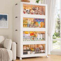 a white cabinet filled with lots of toys and other items in front of a window