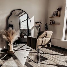 a chair and mirror in a room with wood flooring on the walls, near a large window