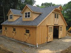 a large wooden barn with two garages on the front and one in the back