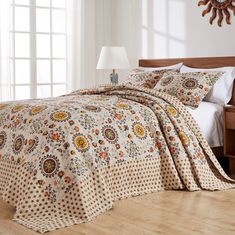 a bedroom with a bed covered in a floral print comforter and pillows on top of it