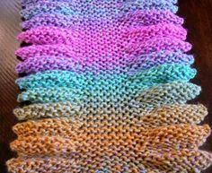 knitted dishcloths in different colors on a wooden table, with one folded over the other