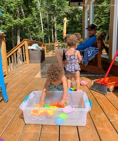 two young children playing with toys on a deck in front of a man and woman