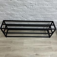 two black metal trays sitting on top of a wooden floor next to a white brick wall