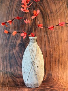 a white vase with red flowers in it