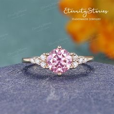 a pink diamond ring sitting on top of a blue rock with flowers in the background