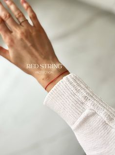 a woman's hand with a red string bracelet on her wrist and the text red string protection