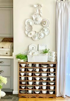 a white clock mounted to the side of a wall next to a bunch of dishes