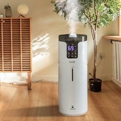 an air purifier is on the floor next to a potted plant