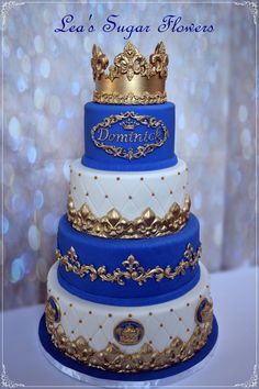 a three tiered cake with gold and blue frosting on the top, topped with a crown