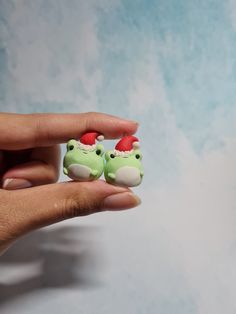 someone is holding two tiny toy animals in their hands, one wearing a santa hat