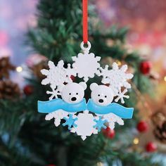 an ornament shaped like two bears hanging from a christmas tree with snowflakes