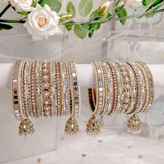 a bunch of bracelets that are on top of a white cloth with flowers in the background