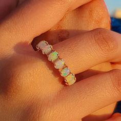 a woman's hand holding an opalite ring in front of her face