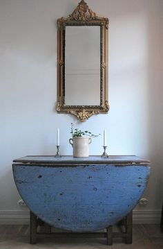 an old blue bathtub with a mirror above it and candles in front of it