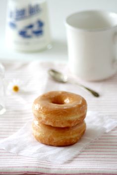 three glazed donuts sitting on top of a napkin next to a cup and spoon