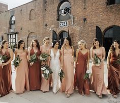 a group of women standing next to each other in front of a brick building holding bouquets