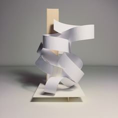 a sculpture made out of white paper on top of a wooden stand with tape attached to it