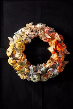 a wreath made out of paper flowers on a black door with the letter o in it