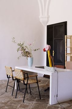 a table with chairs and a vase on it