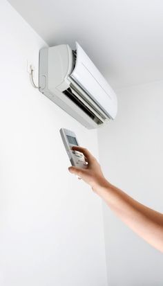 a person holding a cell phone in their hand and an air conditioner hanging from the ceiling