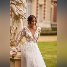 a woman standing next to a statue wearing a wedding dress