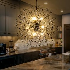 a chandelier hanging from the ceiling in a kitchen with granite counter tops and cabinets