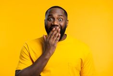 a man in a yellow t - shirt is making a surprised face with his hands