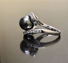 a black pearl and diamond ring on a table