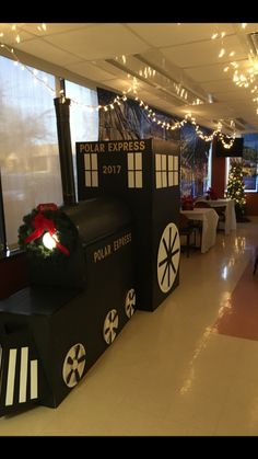 a room decorated for christmas with lights on the ceiling and decorations in front of windows