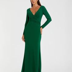 a woman in a long green dress is standing with her hands on her hips and looking at the camera