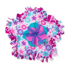 a pink, blue and purple flowered pillow with a bow on the top that has ruffles around it